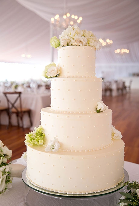 A four-tiered white wedding cake with piped dot details, created by Kennedy Confections.