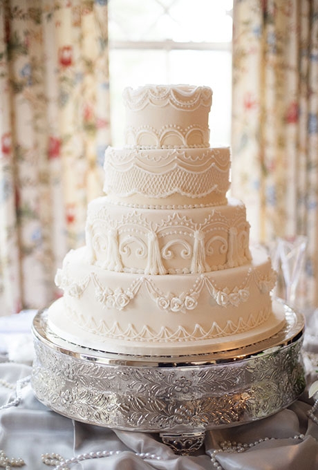 A four-tiered white wedding cake with intricate piped details created by Dianna Tornow Cakes.