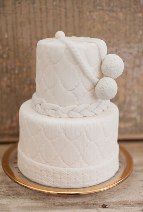 A two-tiered nautical white wedding cake with braided details and roping, created by La Patisserie Chouquette.